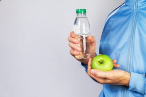 person-holding-a-bottle-of-water-and-an-apple_1220-827