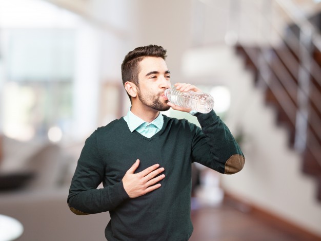 young-man-drinking-water-with-one-hand-on-his-chest_1149-1241